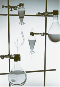 Photograph  of chemistry lab equipment, includes glass beakers clamped on tubing.